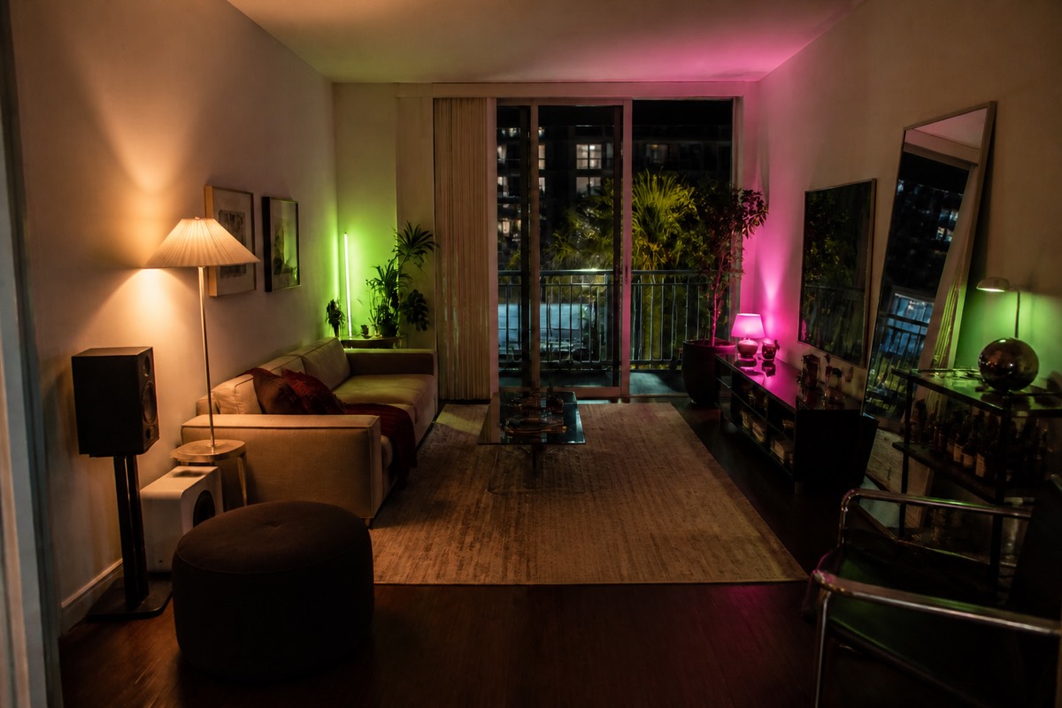 The same living room with the recommended move rendered in: neon low, mirrors up, bar cart in the dead corner